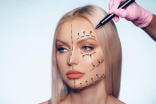 Beautiful blonde woman with markings for plastic surgery on her face, woman portrait
