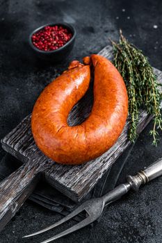 Bavarian Smoked sausage on a wooden rustic board with thyme. Black background. Top view.