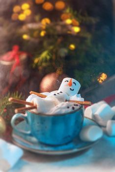 Christmas background with a marshmallow man lying in a mug with cocoa, in the background a Christmas tree with toys, a garland and gifts