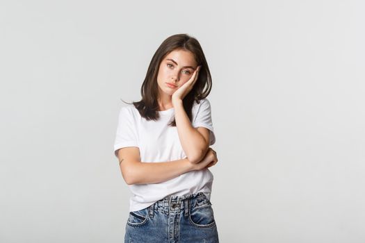 Tired or annoyed young woman leaning on hand and looking indifferent.