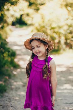 Portrait of cute girl dressed in bright standing in the forest road.