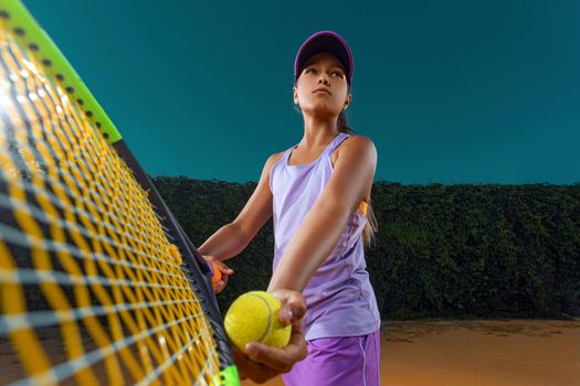 Beautiful girl tennis player with a racket on dark background wiht lights