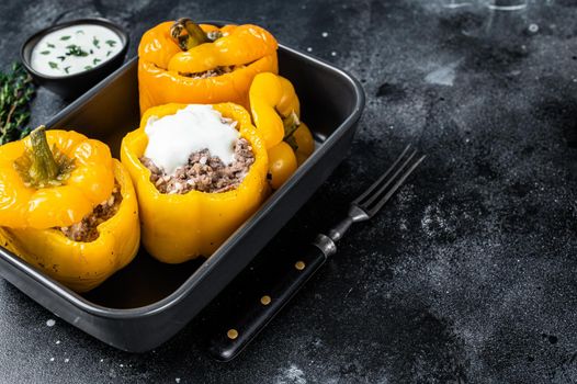 Baked yellow Sweet bell pepper stuffed with beef meat, rice and vegetables. Black background. Top view. Copy space.