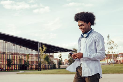 Outdoor Portrait Of Afroamerican Young Man Using Mobile In The Street.