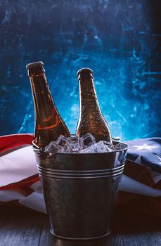 two bottles of beer in an ice bucket with the American flag lying nearby. Independence Day celebration concept