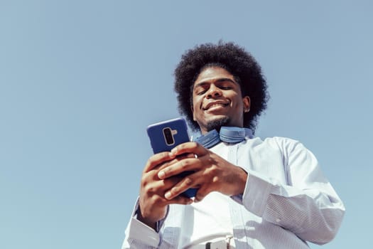 Happy afro guy using his mobile phone. View from below