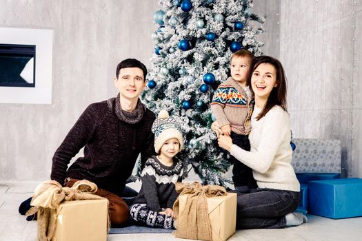 Portrait of four nice attractive lovely cheerful dreamy friendly big family spending celebrating newyear sitting on floor. Family in the morning near the Christmas tree. Family And Christmas Presents.