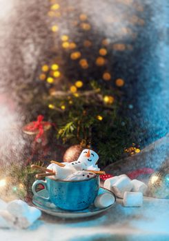 Christmas background with a marshmallow man lying in a mug with cocoa, in the background a Christmas tree with toys, a garland and gifts