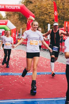 POLTAVA, UKRAINE - 1 SEPTEMBER 2019: A sporty woman on jumping utilities reaches finish line during Nova Poshta Poltava Half Marathon.