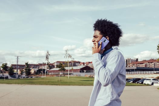 Close-up portrait of young afro man talking by phone outdoors