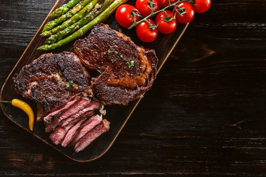 Dinner for two juicy delicious steaks, asparagus with parmesan and vegetables.