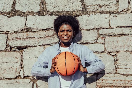 Young african afro man leaning on wall with basket ball looking to the camera
