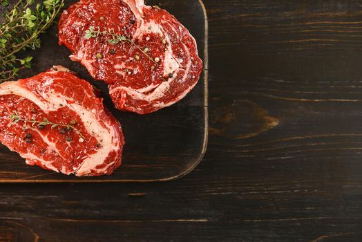 two raw marbled beef steaks in olive oil and spices ready for frying. dinner party concept