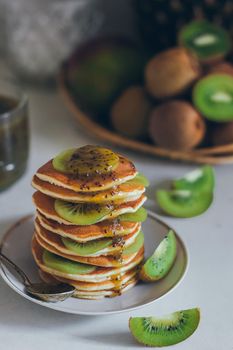 Plate of pancakes dripping with kiwi jam with kiwi pieces. Shrovetide Maslenitsa Butter Week festival meal. Shrove Tuesday. Pancake day