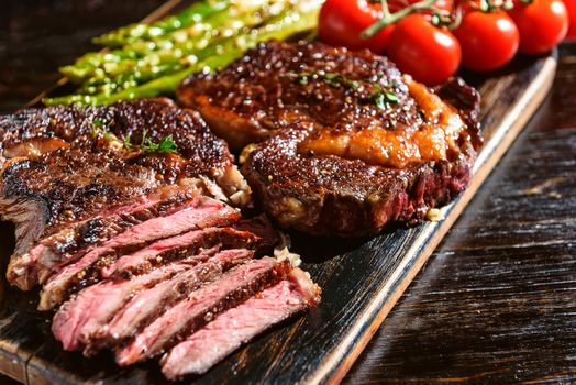 Dinner for two juicy delicious steaks, asparagus with parmesan and vegetables.