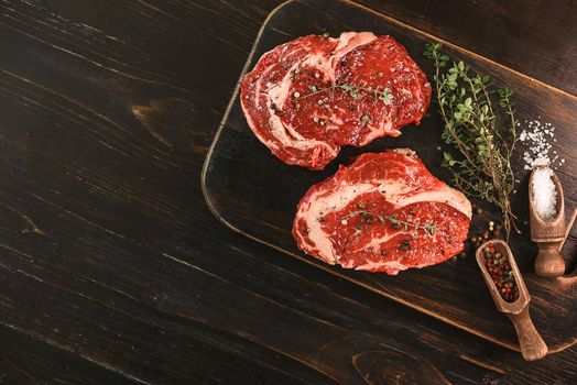 two raw marbled beef steaks in olive oil and spices ready for frying. dinner party concept