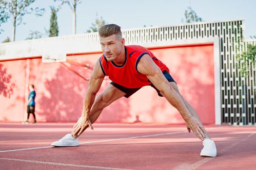 sports man in a red t-shirt on the sports ground doing exercises. High quality photo