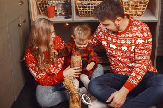 People reparing for Christmas. People playing with their daughter. Family is resting in kitchen. Child in a red dress.