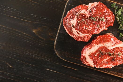 two raw marbled beef steaks in olive oil and spices ready for frying. dinner party concept