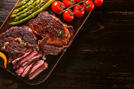 Dinner for two juicy delicious steaks, asparagus with parmesan and vegetables.