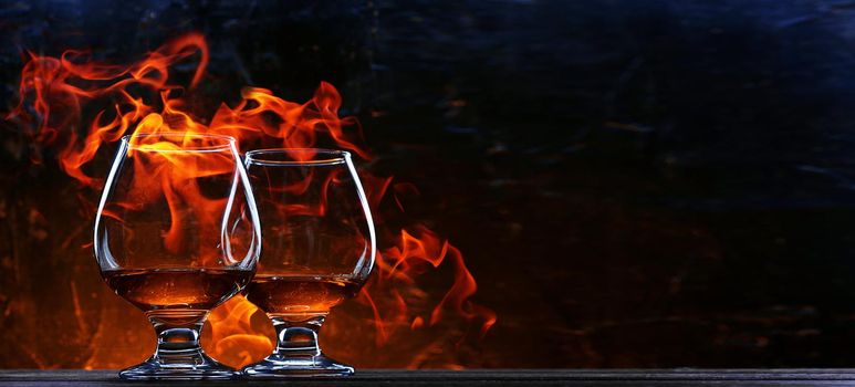 French brandy in a classic glass on the background of fire for two. concept of unhurried evening talk of two friends over a glass of brandy