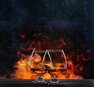 French brandy in a classic glass on the background of fire for two. concept of unhurried evening talk of two friends over a glass of brandy