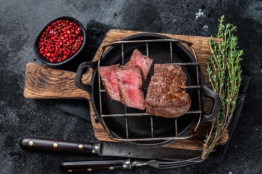 Grilled fillet mignon beef steak on a grill. Black background. Top view.