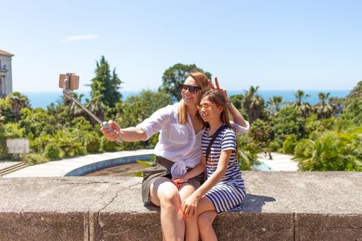 Happy family mother and her adorable little daughter on summer vacation taking selfie with smartphone.