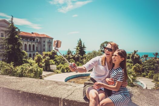 Happy family mother and her adorable little daughter on summer vacation taking selfie with smartphone.