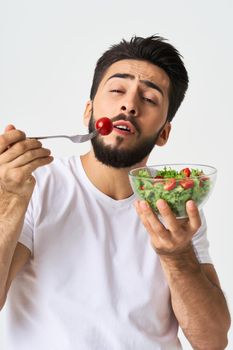 Cheerful man in a white T-shirt with a plate of light green and a healthy meal. High quality photo