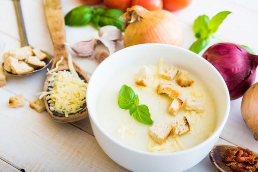 onion soup puree in a white plate with vegetables on the table