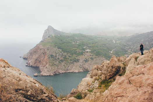 Man on the top of a rock admiring the seaside.