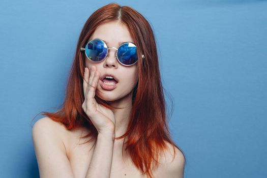 perky red-haired woman in blue glasses bare shoulders posing. High quality photo