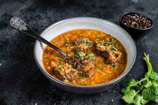 Lamb soup Kharcho with mutton meat, rice, tomatoes and spices in a bowl. Black background. Top view.