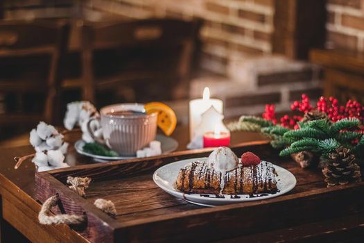 Closeup of a strudel with a strawberry on a Christmas plate near bamboo branch. Christmas breakfast on a wooden table