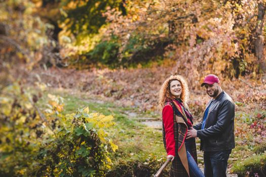 Happy couple in love embraces and has fun outside in the nature background. Woman is pregnant. Happy new parents