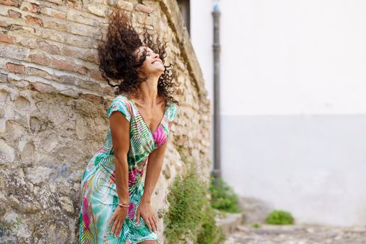 Beautiful brunette middle-aged woman in her 40s wearing spring colorful dress outdoors.