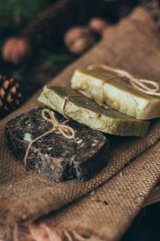 Pieces of beautiful natural handcrafted soap on wooden background with botanical elements, close up view. For relax, health, spa and aromatherapy