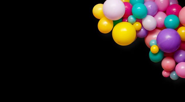 A group of colorful party balloons on a black background with copy space