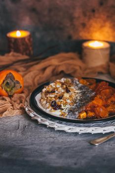Healthy breakfast concept. Oatmeal granola with yogurt, dried fruit, seeds, honey, persimmon in bowl over grey concrete background. Allergy-friendly, gluten free concept.