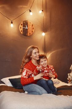 Beautiful mother with child. Family in cristmas atmosphere. Little boy on a bed.