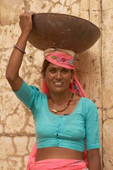 JAIPUR, RAJASTHAN, INDIA - JULY 30, 2008: Female laborers transporting water and plaster in bowls carried on the head during the restoration of a palace inside Amber Fort in Jaipur, Rajasthan, India.