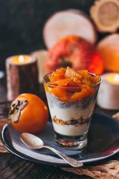 Delicious breakfast: chia seed pudding and persimmon close up in a glass on the table. vertical.