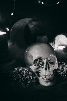 Occult mystic ritual halloween witchcraft scene - human scull, candles, dried flowers, moon and owl. Black and white photo.