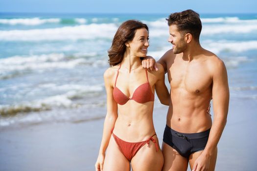 Young couple of beautiful athletic bodies walking together on the beach enjoying their holiday at sea