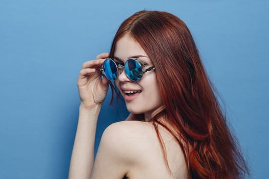 attractive woman with bare shoulders fashionable glasses blue background. High quality photo