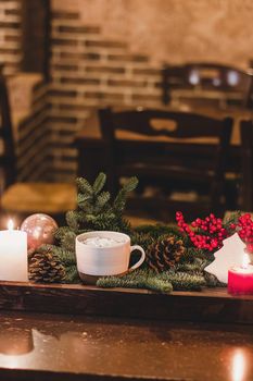 Christmas hot chocolate with mini marshmellows in an old ceramic mug with candles on a wooden background.