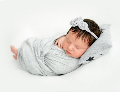 newborn baby girl sleeping sweetly on a little pillow