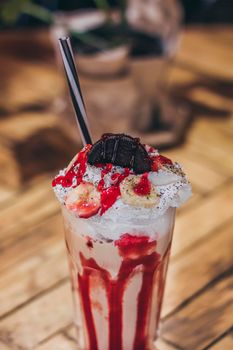 A glass with delicious coffee ice cream red shake on the wooden background.