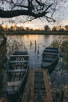 A boat near the river shore filled with water and golden autumn leavesin sunset time.